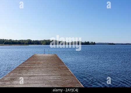 Quai de baignade en bois avec échelle en métal sur lac bleu calme journée ensoleillée sur la nature Finlande station naturelle idyllique Banque D'Images