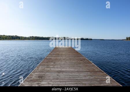 Quai de baignade en bois avec échelle en métal sur lac bleu calme journée ensoleillée sur la nature Finlande station naturelle idyllique Banque D'Images