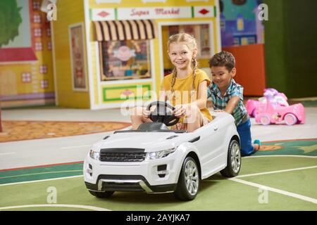 Petit garçon poussant jouet voiture intérieure. Banque D'Images