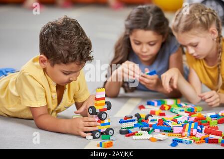 Enfants jouant ensemble dans la salle de classe à la maternelle. Banque D'Images