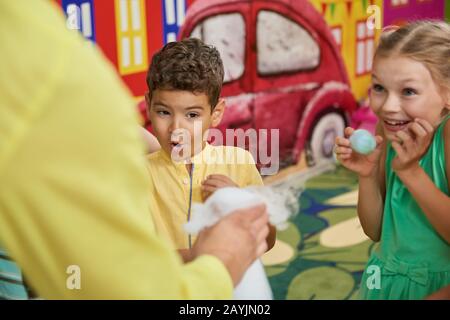 Joyeux enfant à regarder un spectacle de chimie à la fête de naissance. Banque D'Images