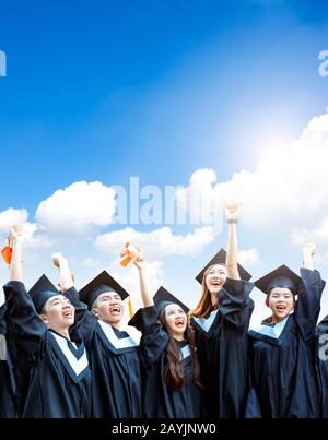 les étudiants heureux qui ont obtenu leur diplôme possèdent des diplômes sur le cloud Banque D'Images