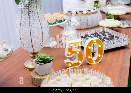 Un beau gâteau pour le 50ème anniversaire décoré. Fête d'anniversaire de table avec un gâteau blanc à deux étages décoré de roses jaunes et de son vert Banque D'Images