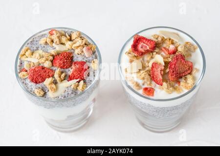 Deux verres de pudding de graines de chia de nuit avec lait d'amande, yaourt, granola maison, fraises séchées et amandes. Super-cuisine et cuisine végétalienne Banque D'Images