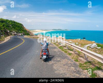 Une personne qui fait de la moto sur une route sinueuse en regardant la magnifique côte dans la province de Phu Yen, Nha Trang Quy Nhon, aventure en voyage au Viet Banque D'Images