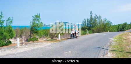 Une personne qui fait de la moto sur une route sinueuse en regardant la magnifique côte dans la province de Phu Yen, Nha Trang Quy Nhon, aventure en voyage au Viet Banque D'Images