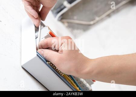 Un électricien monte le panneau de commande du standard électrique grand public pour le boîtier domestique pour la distribution et l'alimentation électrique Banque D'Images