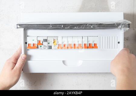 Un électricien monte le panneau de commande du standard électrique grand public pour le boîtier domestique pour la distribution et l'alimentation électrique Banque D'Images