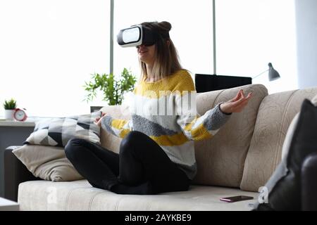 Méditation à la maison sur le canapé à l'aide de lunettes virtuelles. Banque D'Images