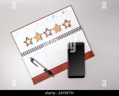 Un ordinateur portable ouvert en cuir se liant avec un smartphone et un stylo sur un fond gris. Le concept de croissance des affaires et de haut niveau de service. S'Efforcer Banque D'Images