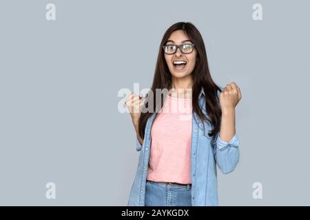 La jeune fille indienne excitée gagnante célèbre le succès isolé sur fond gris Banque D'Images