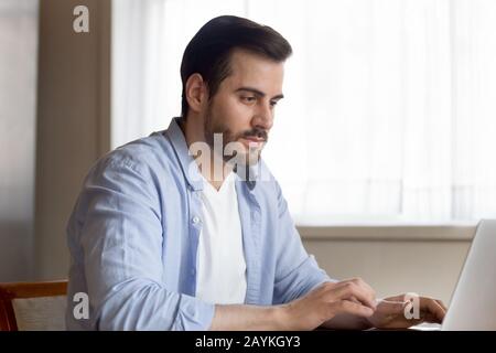 Homme caucasien concentré occupé à travailler sur un ordinateur portable Banque D'Images