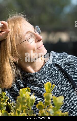 Femme senior à yeux fermés aime l'extérieur avec le visage vers le soleil. Femme plus âgée avec lunettes Banque D'Images