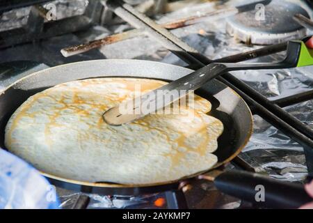 Une femme fait de fines crêpes dans une poêle à frire dans la cuisine sur une cuisinière à gaz Banque D'Images