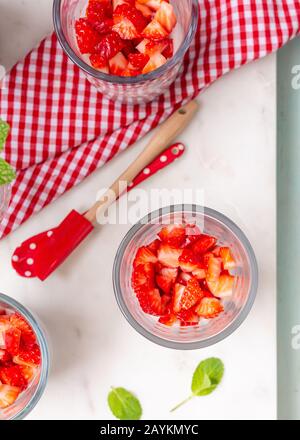 Vue en hauteur d'un verre sain et antioxydant plein de morceaux de fraise avec miel et chia. Une serviette colorée et une cuillère illuminent la scène. Banque D'Images