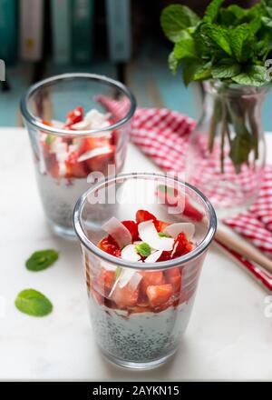 Vue en hauteur et vue rapprochée d'un verre avec des morceaux de fraise. Certaines feuilles de menthe se trouvent sur la planche en marbre. Un deuxième verre double se trouve derrière le premier. Banque D'Images