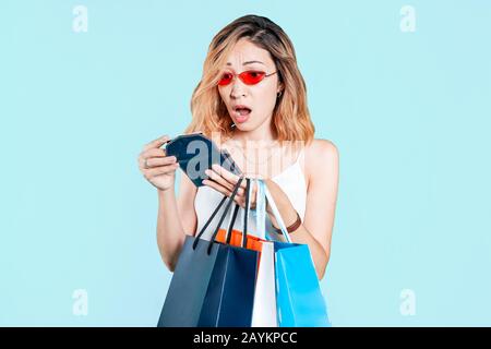 Frustrée et surprise, la fille asiatique regarde un portefeuille vide après les achats. Concept du budget familial et des finances personnelles et des prêts personnels Banque D'Images