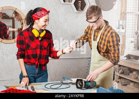 Les charpentiers d'homme et de femme travaillent ensemble dans un atelier sur le bois. Coopération et concept de col bleu Banque D'Images