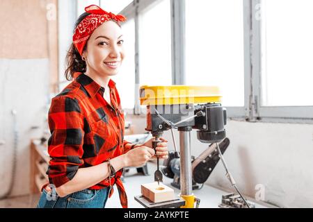 Une femme asiatique forte et indépendante travaille sur une machine de forage dans une usine ou un atelier. Col bleu Banque D'Images
