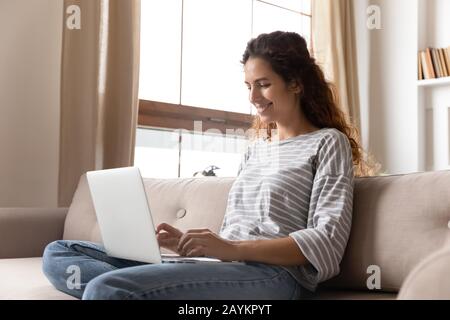 Heureuse jeune femme attrayante utilisant l'ordinateur. Banque D'Images