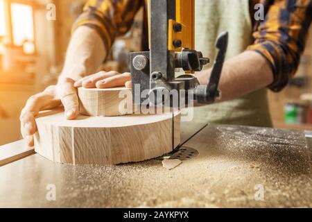 Gros plan sur les mains d'un homme travaillant sur une machine avec une pièce en bois Banque D'Images