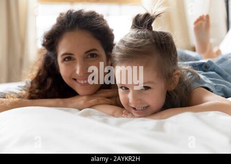 Heureuse adorable femme reposant sur un lit avec petite fille maternelle. Banque D'Images