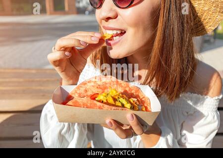 Bonne fille asiatique mangeant taco dehors. Cuisine mexicaine fastfood. En-cas savoureux et épicé dans le parc Banque D'Images