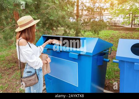 Une femme asiatique heureuse jette du papier dans la poubelle. Concept de tri des déchets Banque D'Images