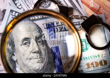 Dollars américains sous une loupe et des menottes Banque D'Images