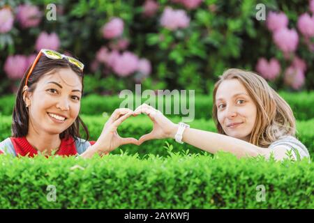 Joyeux amis qui s'amusent dans un parc fleuri au printemps Banque D'Images