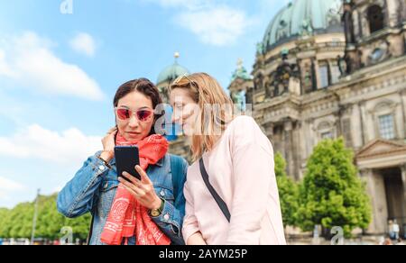 Deux filles amis voyageur à l'aide de l'application téléphone mobile tout en marchant dans la ville de Berlin. Concept de connexion Internet Wi-fi en Europe Banque D'Images