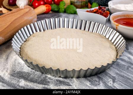 Pâte à pizza bouchées pour la cuisson avec sauce tomate, basilic et autres ingrédients. Banque D'Images