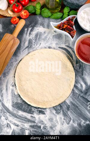 Pâte à pizza bouchées pour la cuisson avec sauce tomate, basilic et autres ingrédients. Banque D'Images