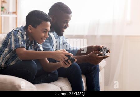 Afro père et fils jouant à des jeux vidéo avec des joysticks Banque D'Images