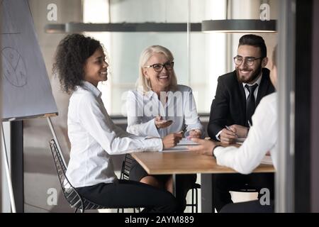 Des employés de bureau multinationaux et souriants discutent lors d'un briefing dans la salle de conférence Banque D'Images