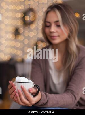 Fille millénaire chauffe les mains avec une tasse de chocolat chaud Banque D'Images