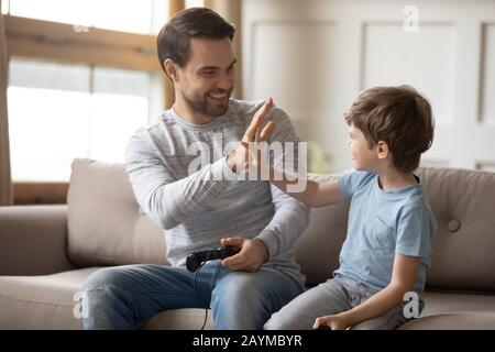 Jeune père excité donnant haut cinq à heureux petit fils. Banque D'Images