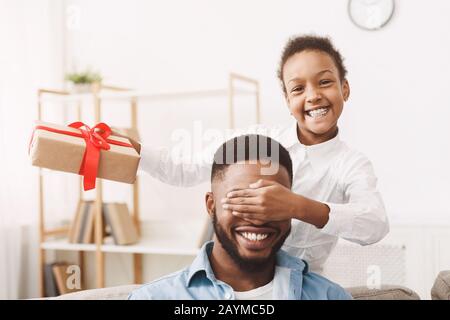 Jolie fille afro qui ferme les yeux du père et fait la surprise Banque D'Images