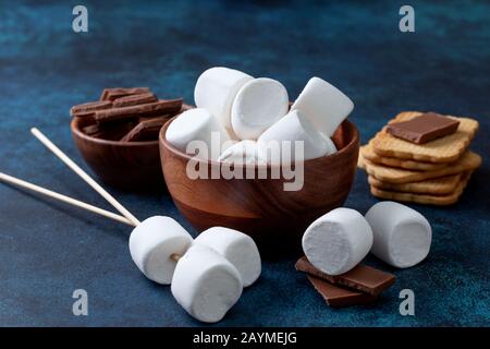 guimauves, chocolat et cookies pour faire des smore sur fond bleu. Banque D'Images