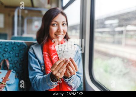 Jeune femme voyageant en train, montrant son billet Banque D'Images