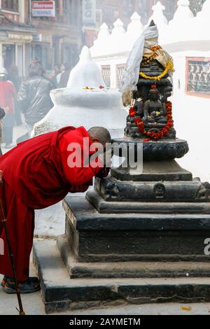 Vieux moine priant à une statue de Boudnath Banque D'Images