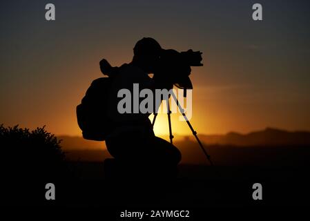 Photographe rétroéclairé au lever du soleil dans le désert Banque D'Images