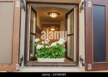 Fenêtre Européenne Typique Avec Volets En Bois Ouverts, Décorés De Fleurs Vertes Banque D'Images
