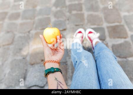 Une femme de tourisme est assise sur une pavée dans la ville et a une collation aux pommes, les voyageurs se reposent et le concept de régime Banque D'Images