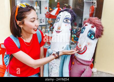 Une touriste féminine se trouve à côté de poupées drôles et les tire derrière une moustache Banque D'Images