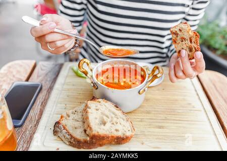 Une femme mange une soupe traditionnelle hongroise de goulash ou de tomate dans une casserole dans un restaurant extérieur Banque D'Images