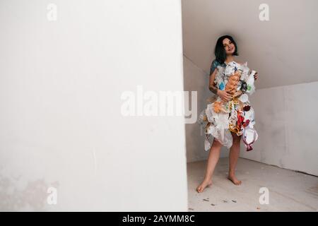 Portrait d'une femme souillée écofighter portant une robe à ordures en plastique et en carton pour favoriser la propagation de la nature de nettoyage de l'environnement par la pollution Banque D'Images