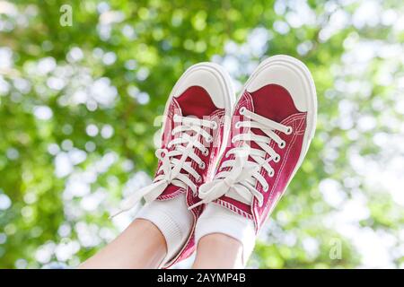 Un pied dans une chaussure de basket sur un fond d'arbre prk, le concept de la mode et des jambes sans varicelle Banque D'Images