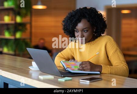 Concentré de Black girl naviguer sur les offres d'emploi sur ordinateur portable Banque D'Images