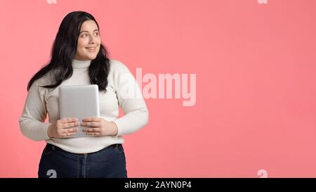 Souriant et petite fille tenant une tablette numérique et regardant de côté Banque D'Images